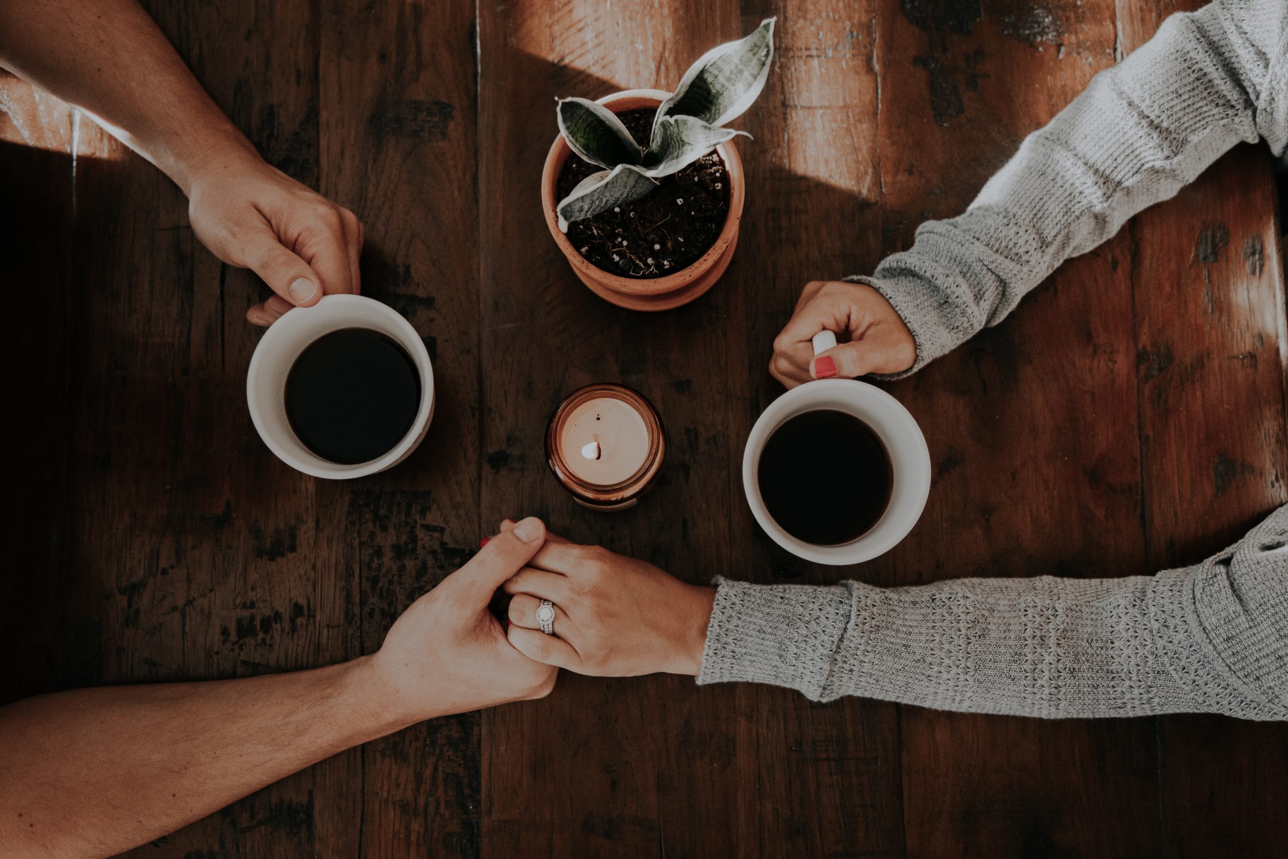 Two people holding hands over coffee